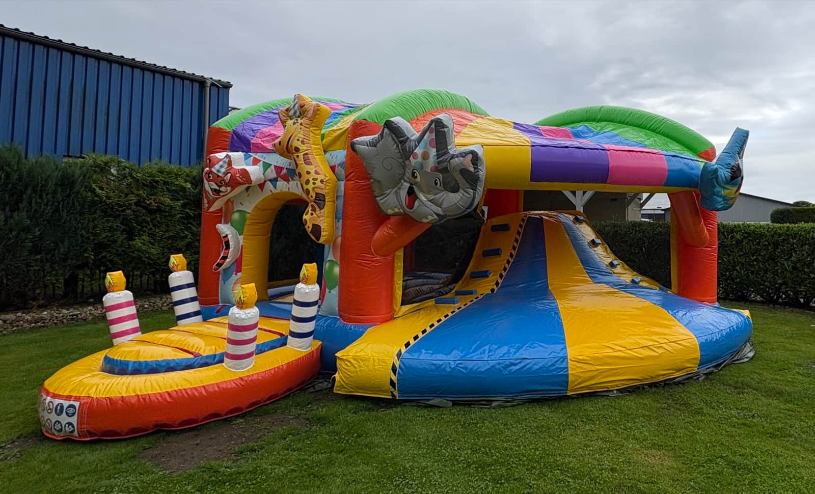 Bunte Party-XL-Hüpfburg mit Rutsche auf einer Rasenfläche